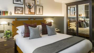 A neatly arranged bedroom with a large bed, a wooden headboard, a bedside table with a lamp, and a wardrobe with glass doors.