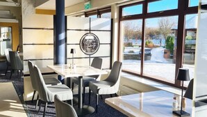 Ein moderner Konferenzraum mit einem großen Tisch, Stühlen und Blick auf eine verschneite Landschaft durch große Fenster.