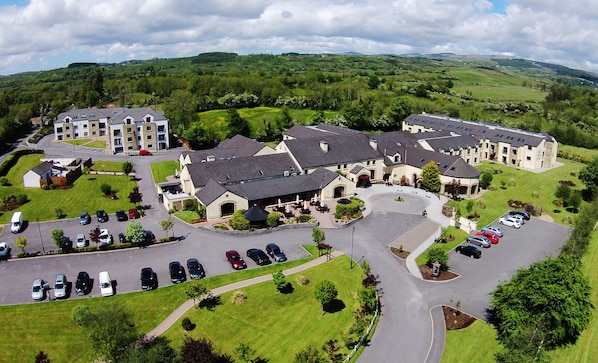 A residential area with multiple houses, a parking lot, and a green landscape in the background. - Mill Park Hotel (Donegal)