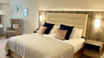 A hotel room with a large bed, two bedside tables, a chair, and a lamp.