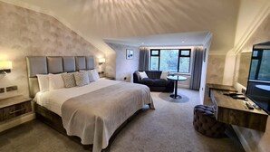 Ein modernes Hotelzimmer mit einem großen Bett, einer Couch, einem Schreibtisch und einem Fernseher.