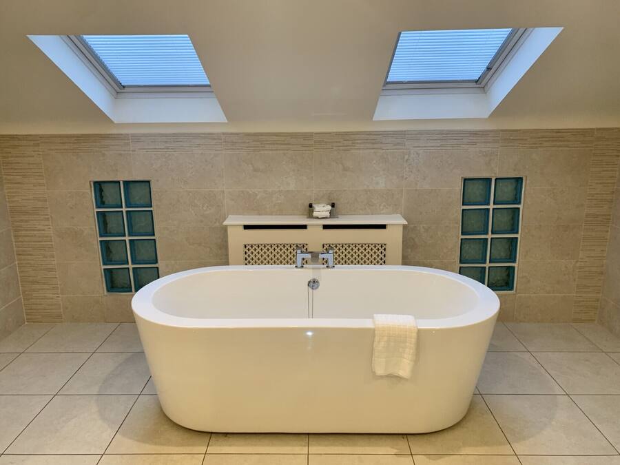 A modern bathroom with a freestanding bathtub, skylights, and a tiled floor.