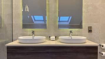 Un baño moderno con dos lavamanos, un espejo grande y un tragaluz.