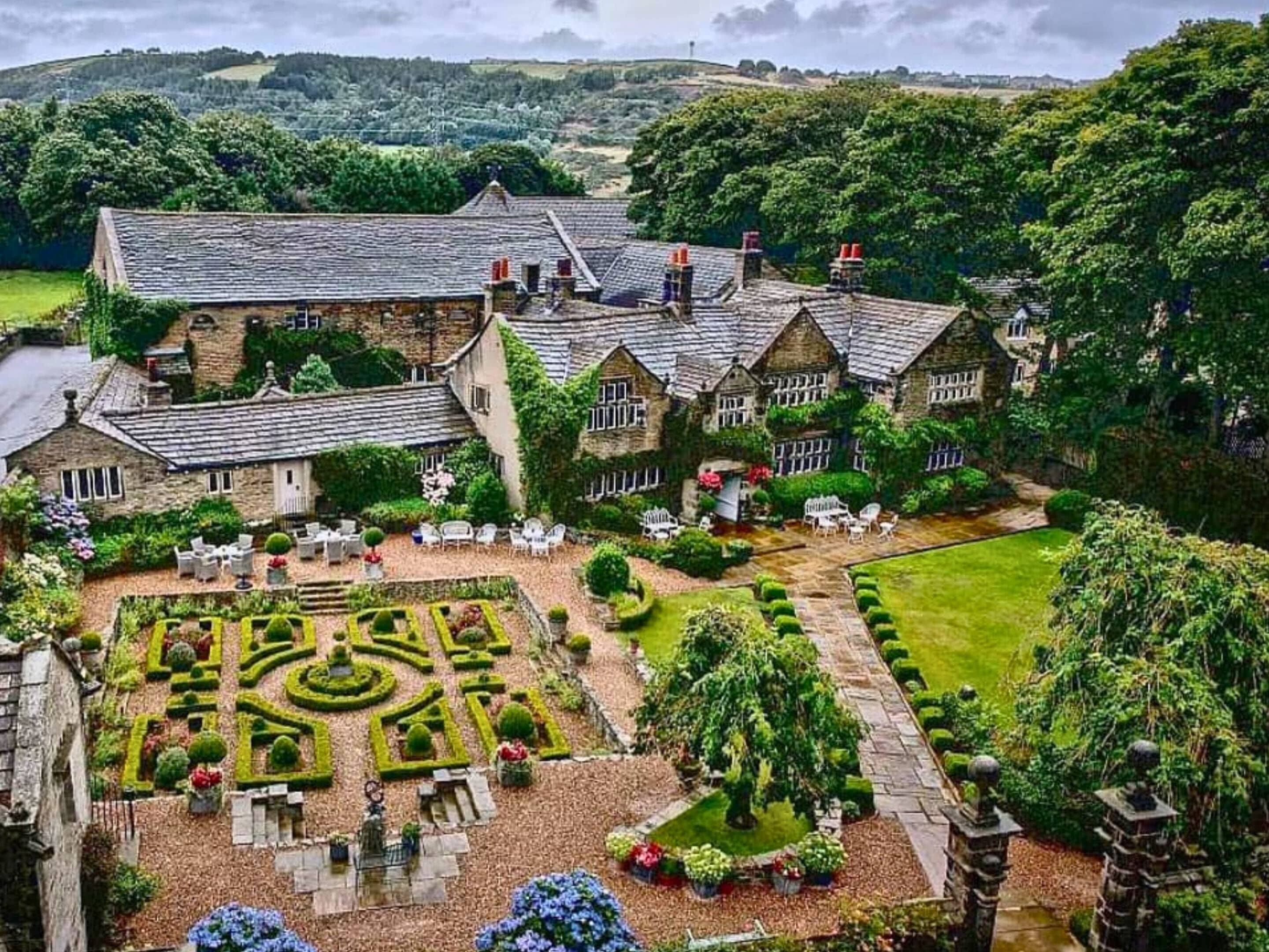 A large stone building with a formal garden and outdoor seating area.