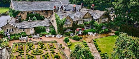 A large stone building with a formal garden and outdoor seating area.