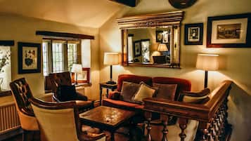 A cozy living room with a fireplace, comfortable seating, and a large mirror.