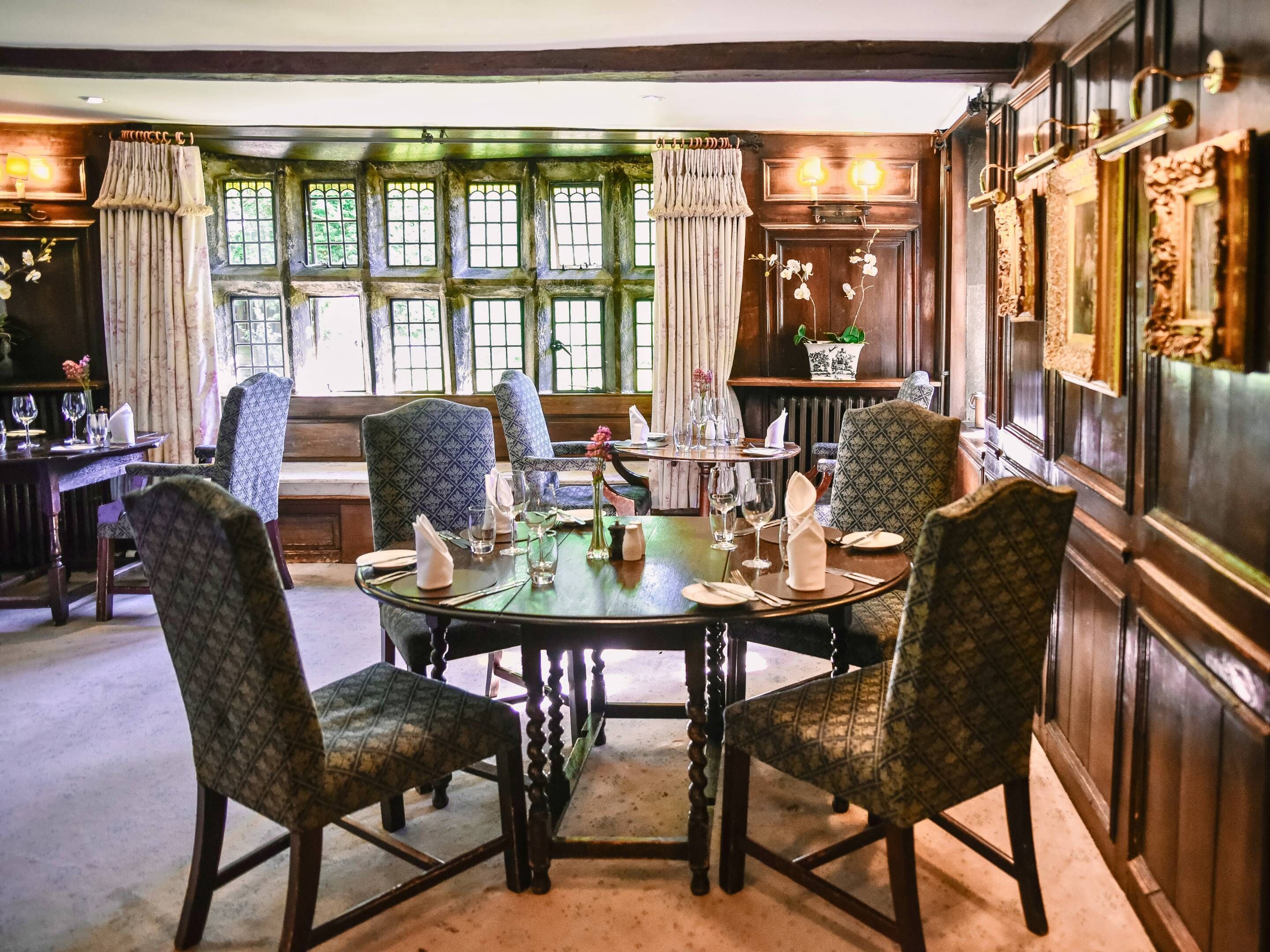 A dining room with a round table set for four, surrounded by patterned chairs.