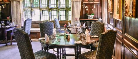 A dining room with a round table set for four, surrounded by patterned chairs.