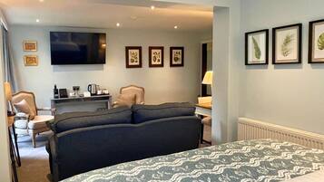 A hotel room with a large bed, a TV, a desk with a lamp, and framed pictures on the wall.