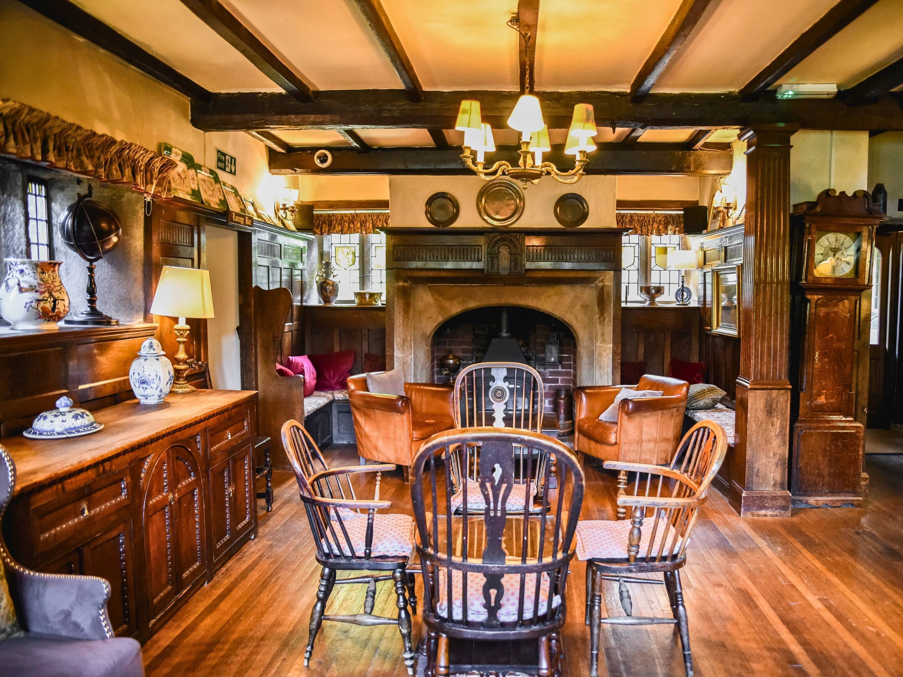 A traditional room with a fireplace, wooden furniture, and a chandelier.