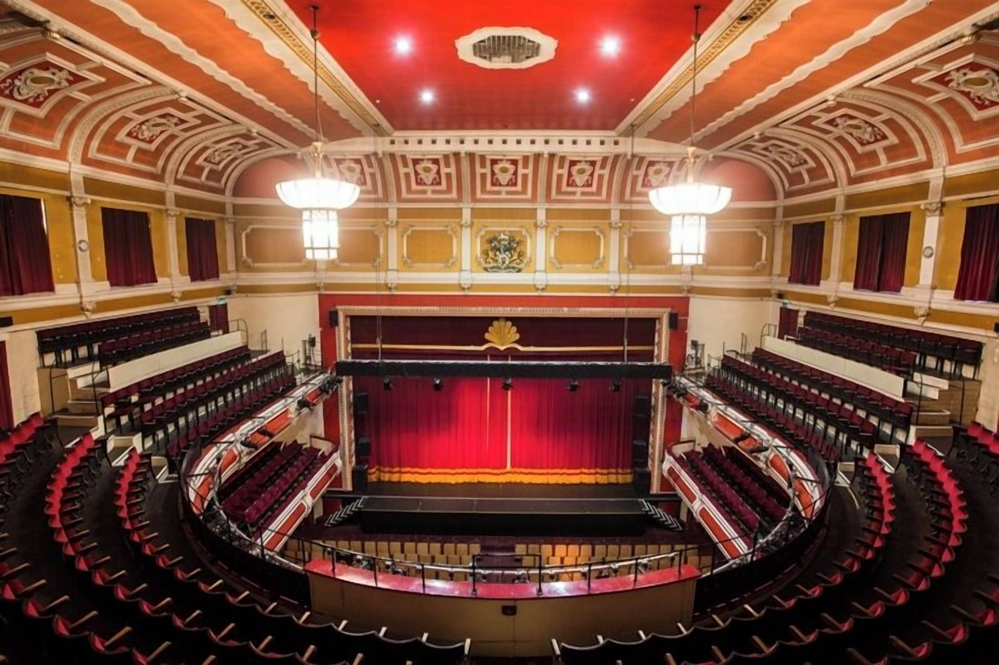 A theater with a central stage, multiple balconies, and ornate ceiling decorations.