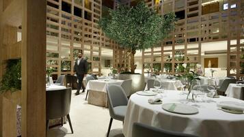 A restaurant with multiple tables, a central tree, and a modern interior design.