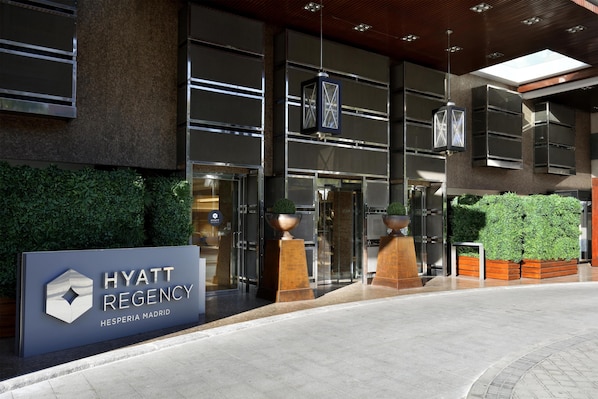 El exterior del hotel Hyatt Regency, con un diseño moderno, amplias puertas de vidrio y un cartel.