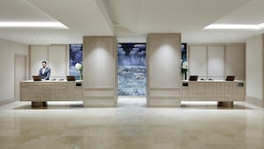 A modern reception area with two reception desks, a large digital screen displaying a waterfall, and a man standing at one desk. - Hyatt Regency Hesperia Madrid (Madrid)
