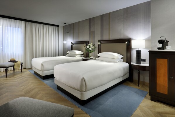 Une chambre d’hôtel avec deux lits, un bureau, une chaise et une table de chevet.