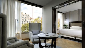 A modern hotel room with a large window, a bed, a seating area with a table, and a chair. - Hyatt Regency Hesperia Madrid (Madrid)