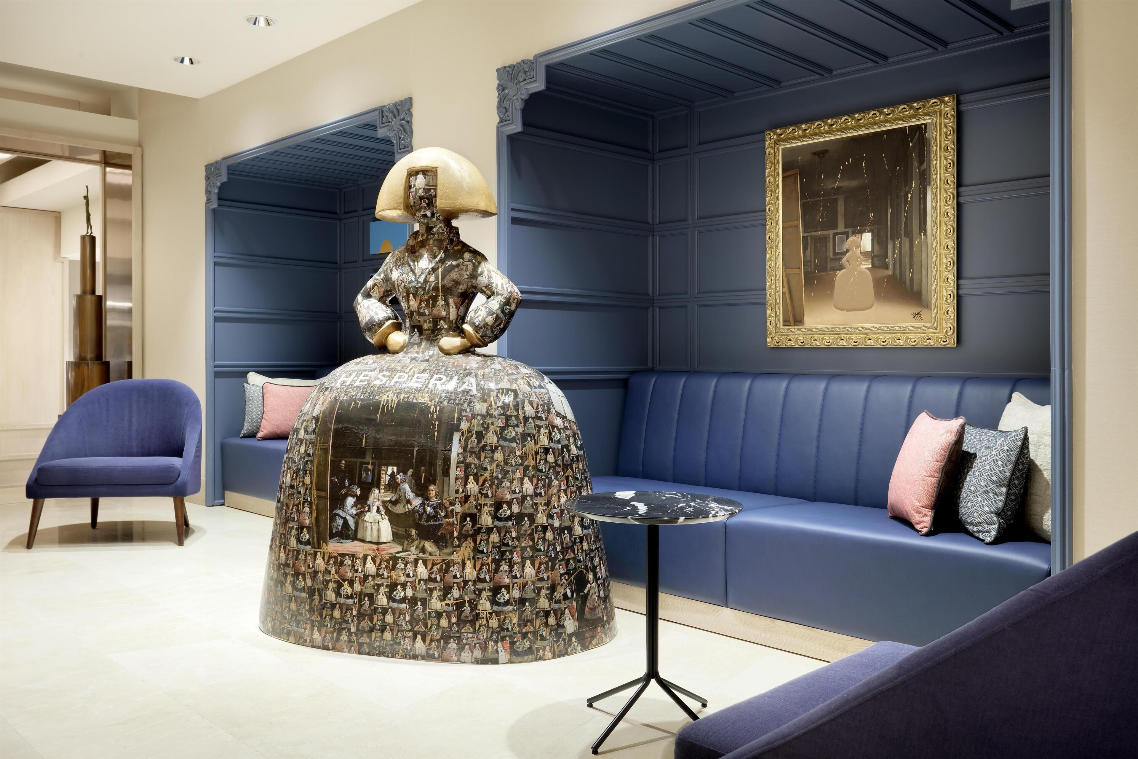 A modern interior with a unique sculpture, a blue sofa, and a framed artwork.