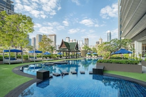 A swimming pool with lounge chairs and umbrellas, surrounded by greenery and modern buildings in the background. - The Athenee Hotel, a Luxury Collection Hotel, Bangkok (Bangkok)