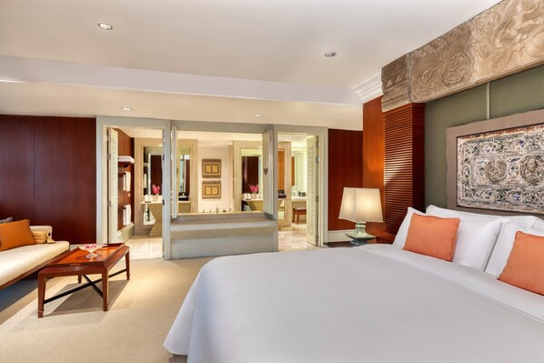 Une chambre d’hôtel dotée d’un grand lit, d’un coin salon avec un canapé et une table basse, d’un bureau avec une lampe et d’un élément décoratif mural.