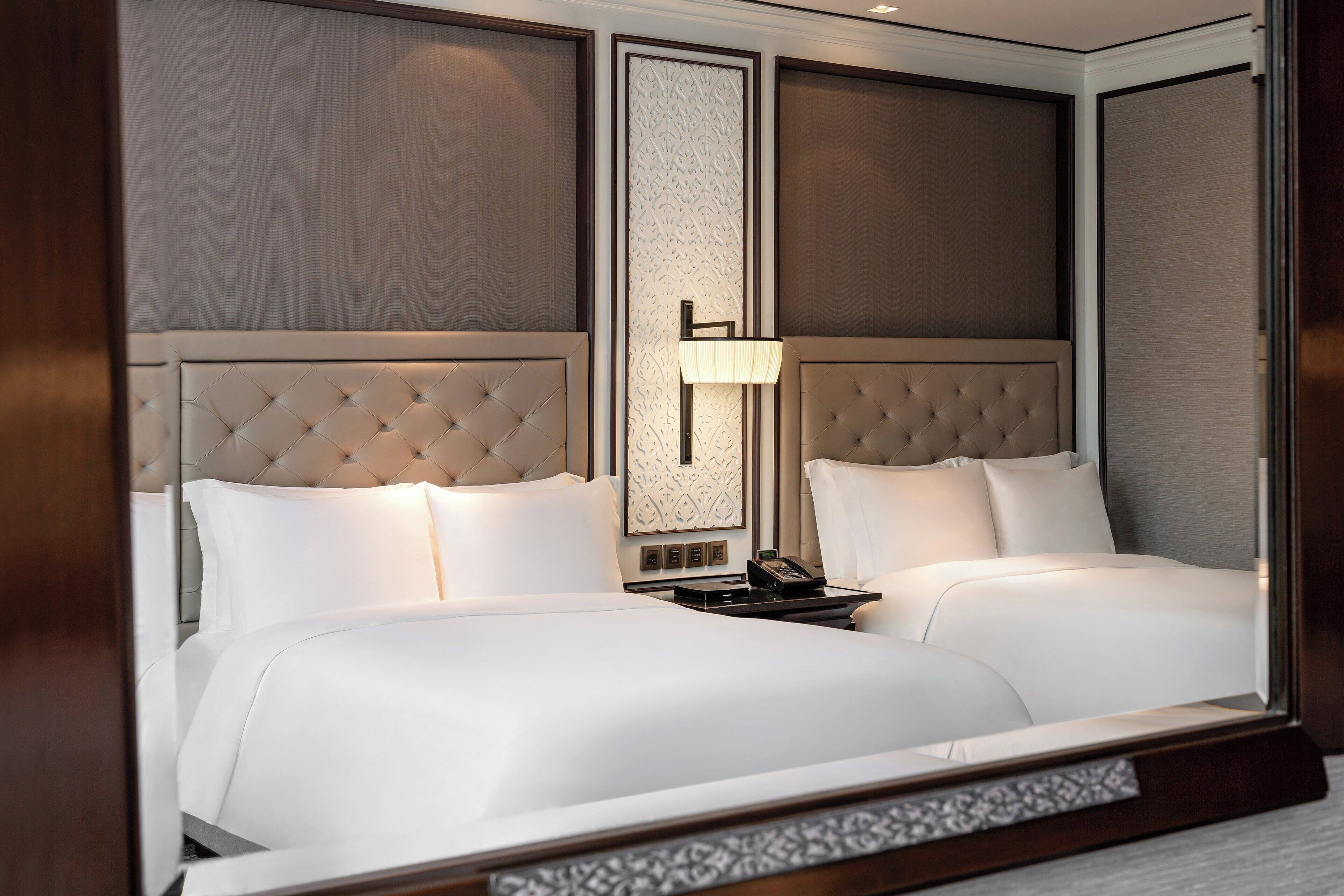 A hotel room with a large bed, a bedside table with a lamp, and a mirror.