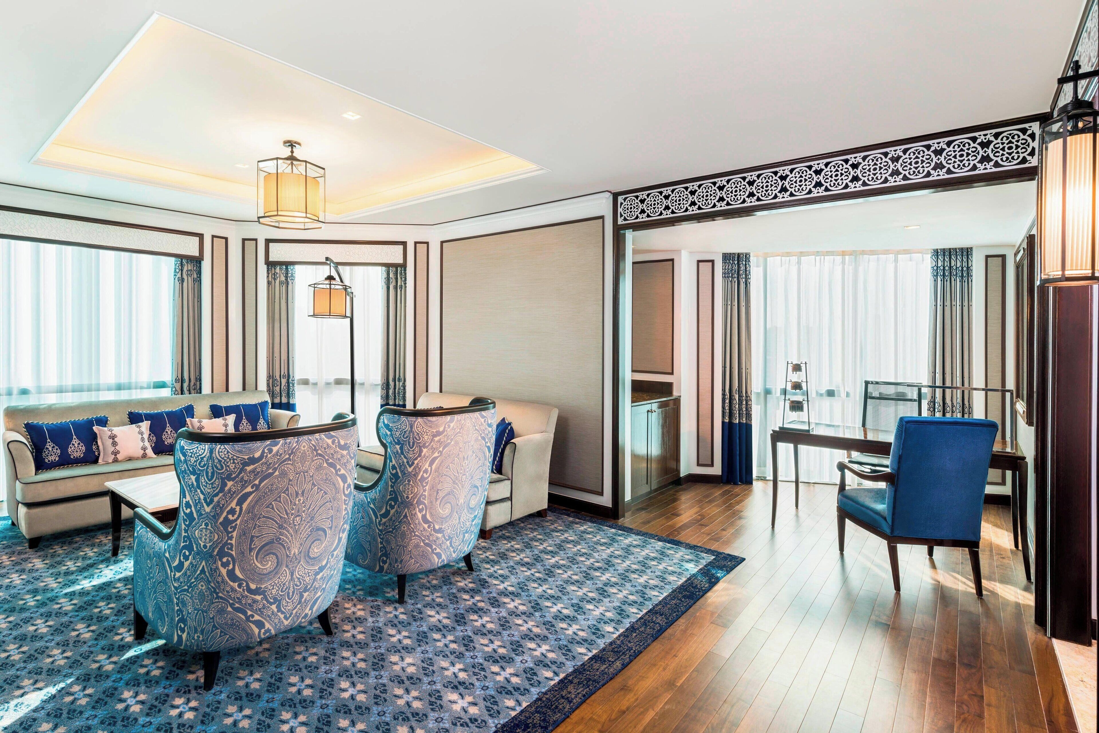 Una habitación de hotel moderna con una zona de estar, una mesa de comedor y vistas a la ciudad.