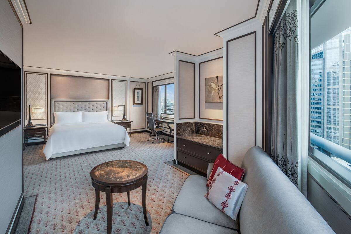 Habitació d'hotel amb un llit gran, un sofà, escriptori i vista a la ciutat.