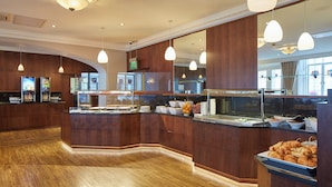 Buffet-alue, jossa on puiset tasot, riippuvalaisimet ja monipuolinen valikoima erilaisia ruokia.