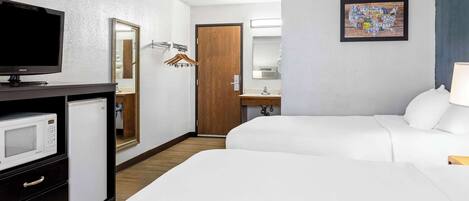 Habitación de hotel con dos camas, un televisor, un microondas, un aparador, una puerta de madera, un baño con espejo y una obra de arte con un mapa en la pared.