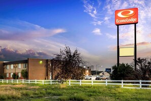 A hotel with a prominent EconoLodge sign, a white fence, and a grassy area in front. - Econo Lodge Billings (Billings)
