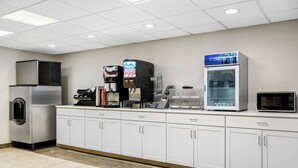 Ett professionellt kök med rostfria köksmaskiner, inklusive ett kylskåp, en kaffemaskin och ett kylskåp med en skylt med texten ”ChillOut”.