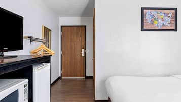 Habitación de hotel con cama, televisión, microondas y puerta de madera.