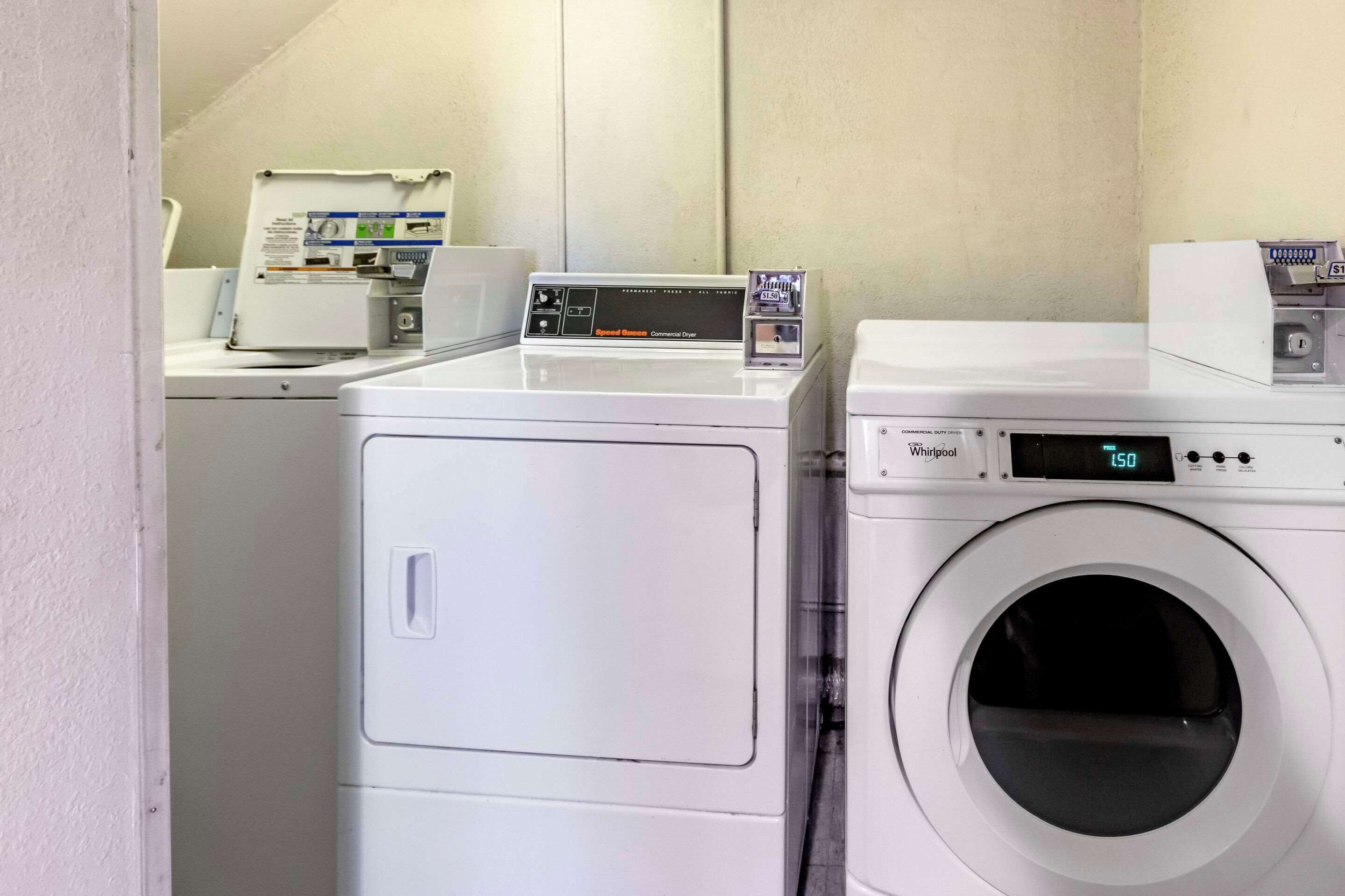 A laundry area with two white washing machines and a dryer.