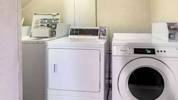 A laundry area with two white washing machines and a dryer.