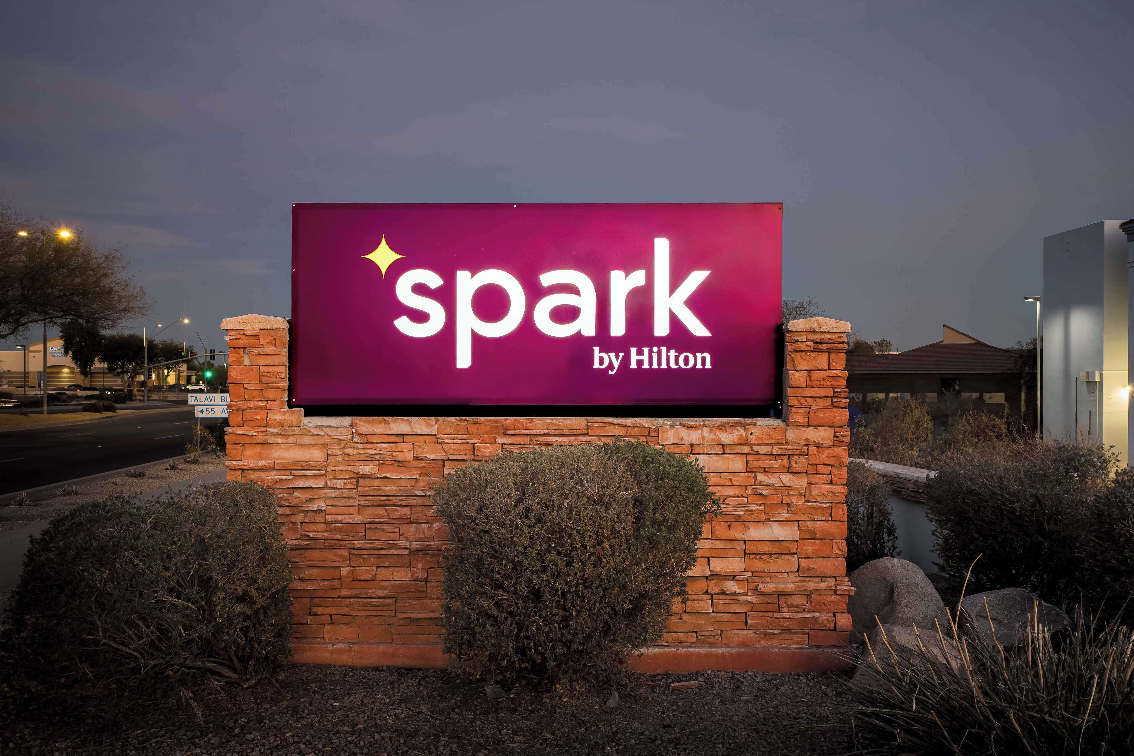 A brick wall with a sign that reads "spark by Hilton" and a street sign for Talavi Blvd.