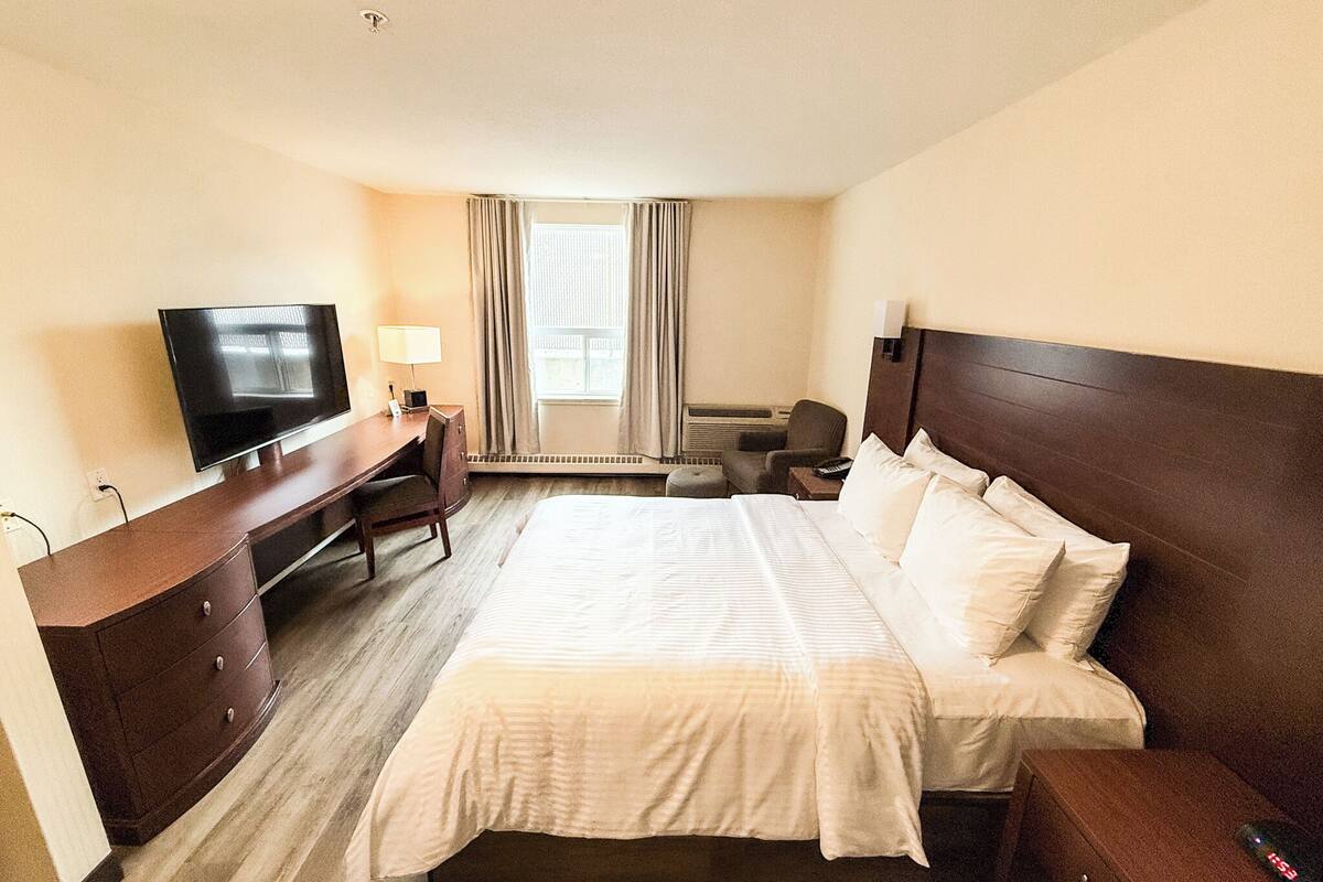 Una habitación de hotel con cama, escritorio, televisor y silla.
