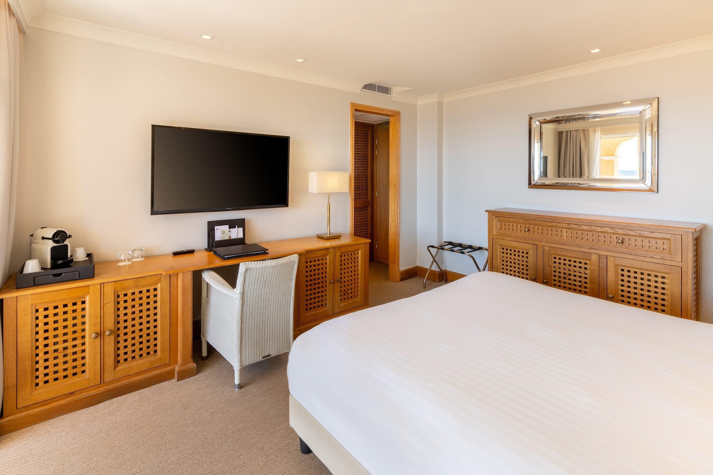 Een hotelkamer met een bed, een bureau met een computer, een televisie en een kledingkast.