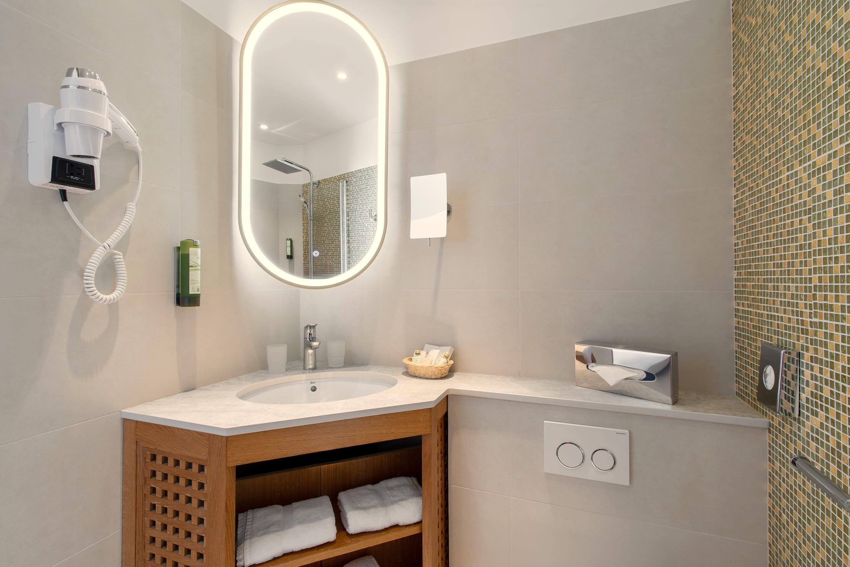A modern bathroom with a large mirror, a hairdryer, a sink, and a towel rack.