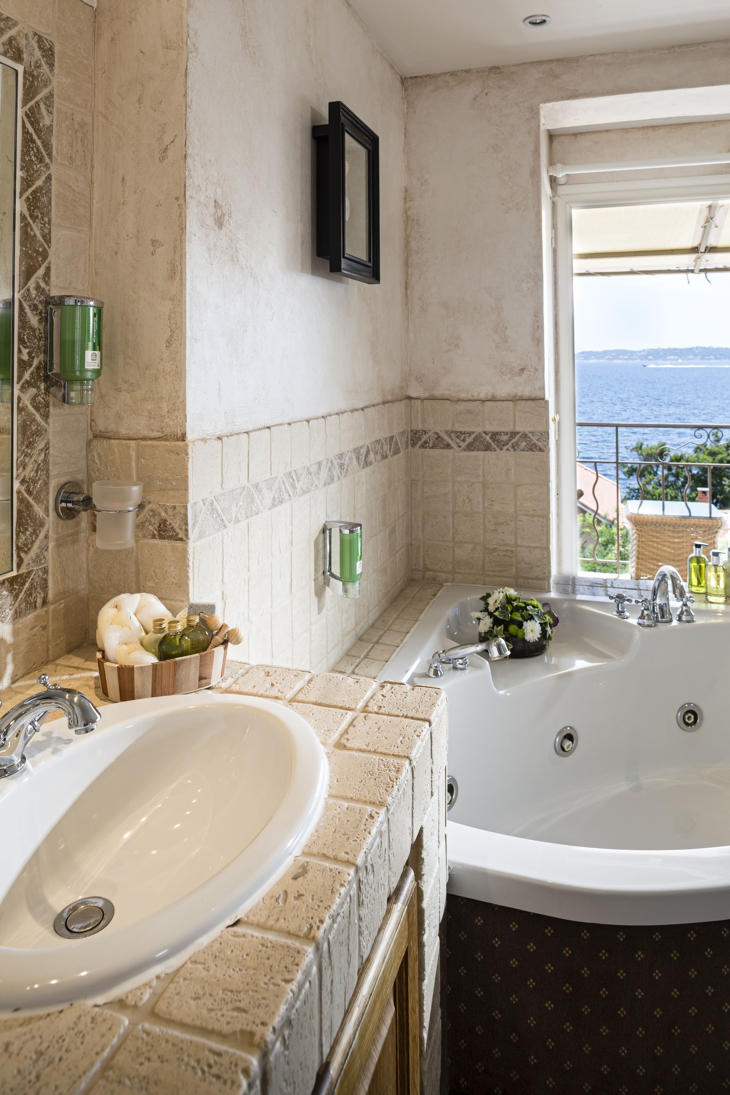 Baño con dos lavamanos, una bañera y vista al mar.