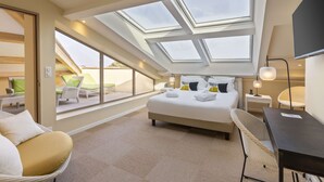 Une chambre d’hôtel avec une lucarne, un lit, un bureau et une chaise.