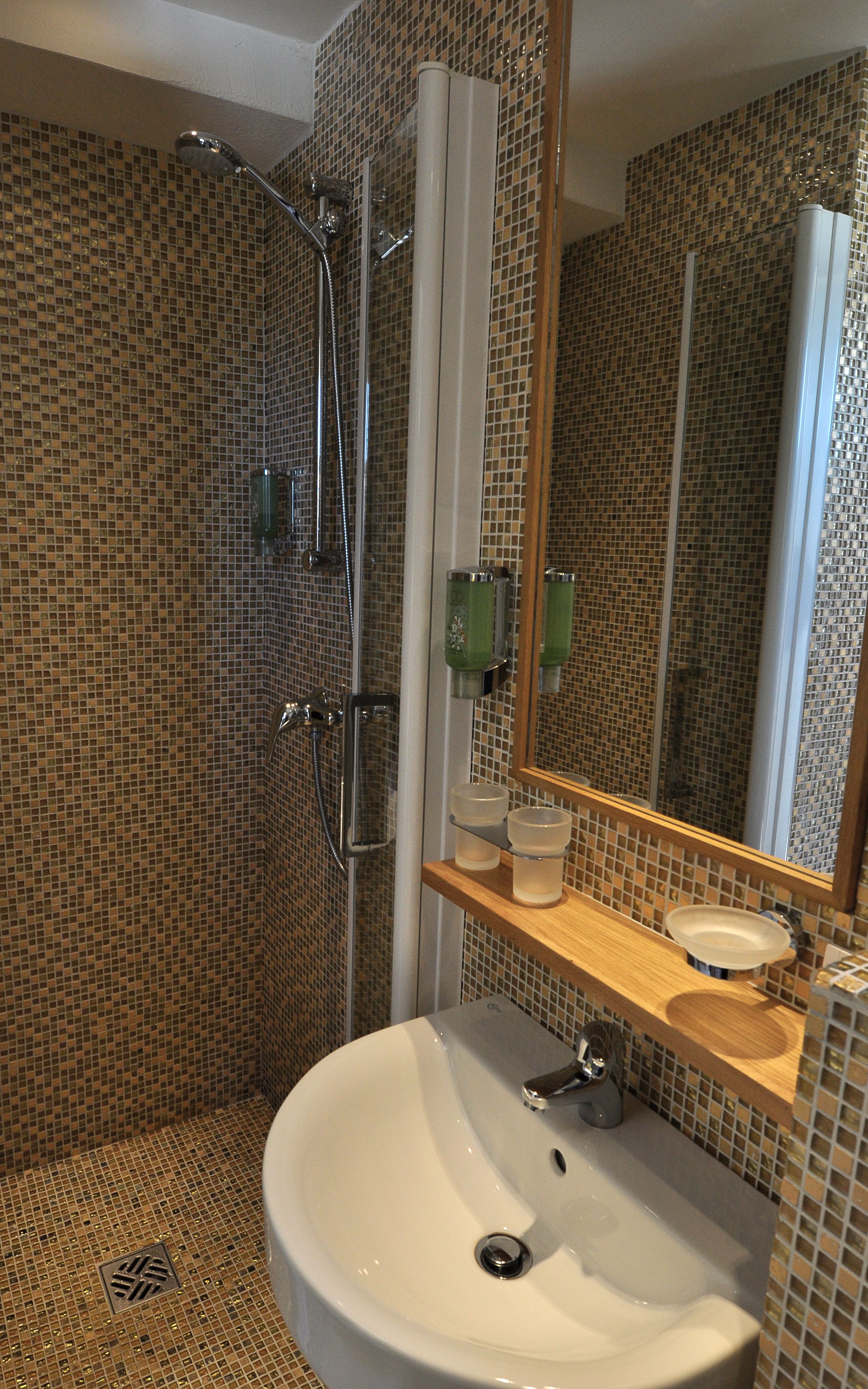 A bathroom with a shower, a sink, and a mirror.