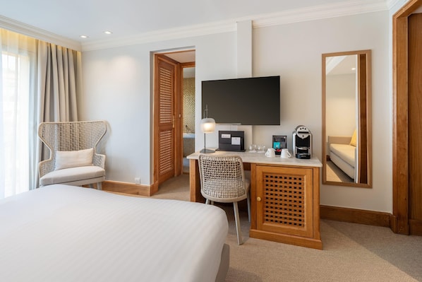 Una habitación de hotel con cama, escritorio con computadora, silla, televisor y espejo.
