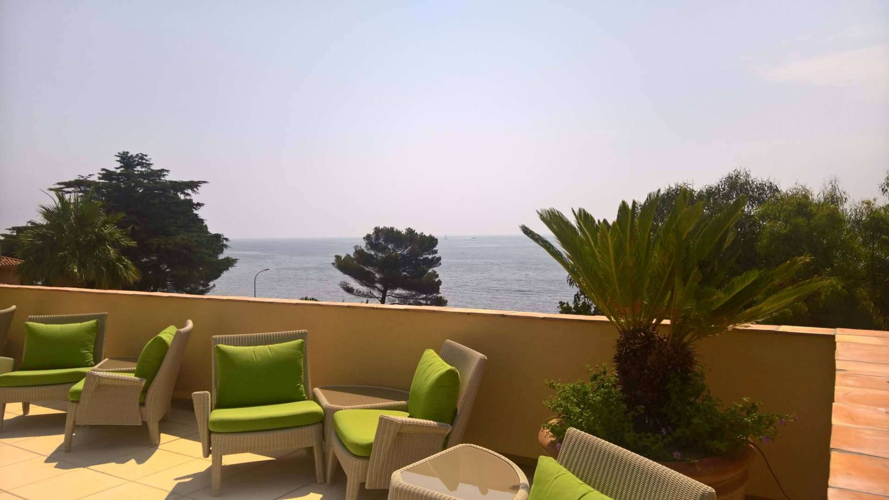 A balcony with wicker furniture and a view of the sea.