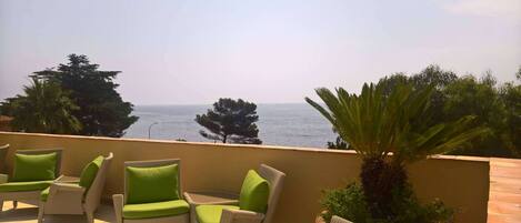 A balcony with wicker furniture and a view of the sea.