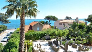 Une propriété située sur la côte, dotée d’un patio, de palmiers et offrant une vue sur la mer.