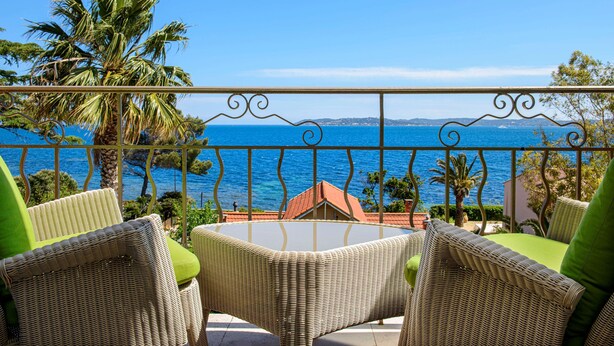 Un balcon doté de meubles en osier et offrant une vue sur la mer.