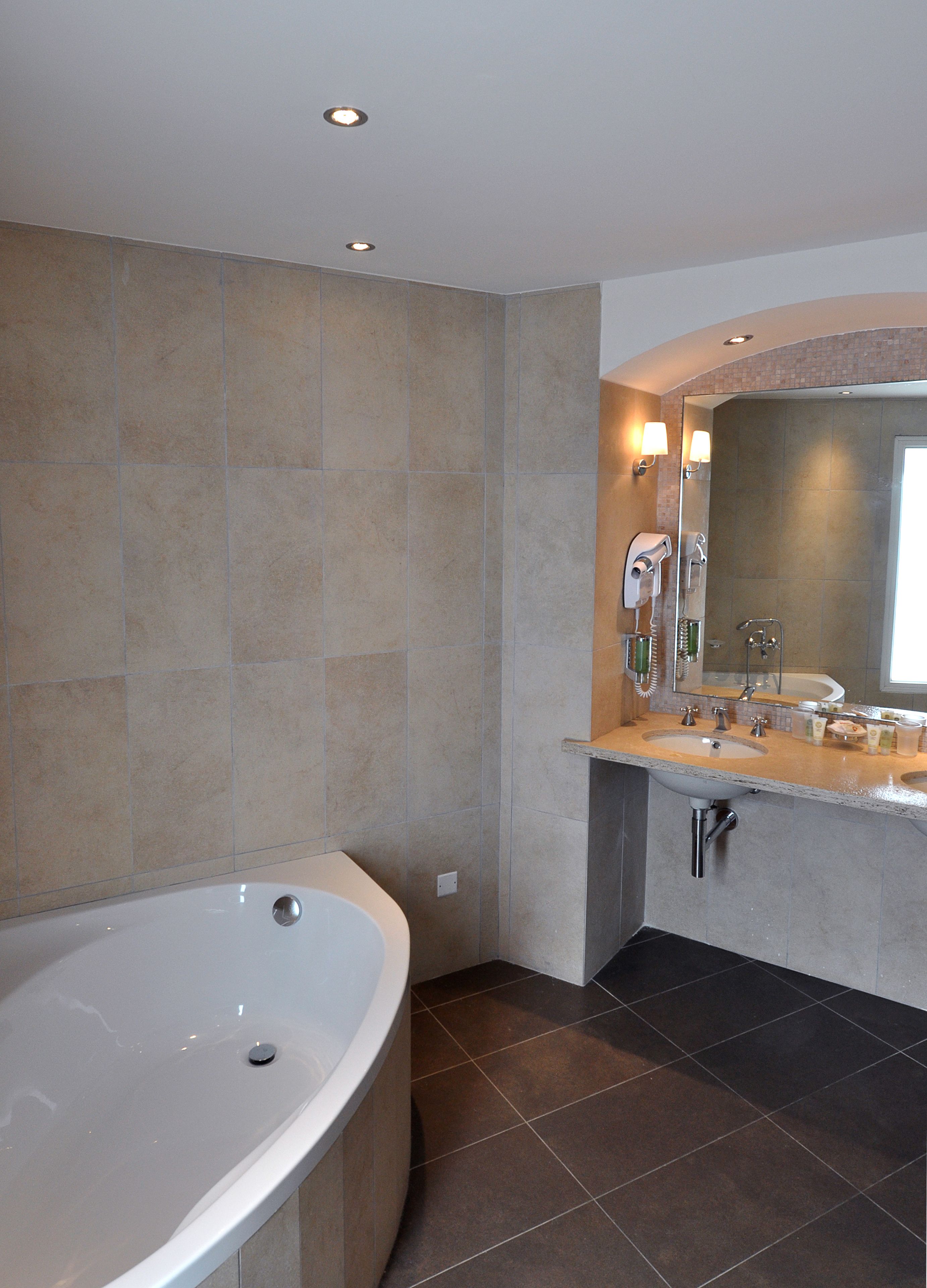 A modern bathroom with a freestanding bathtub, a vanity with a mirror, and a shower area.