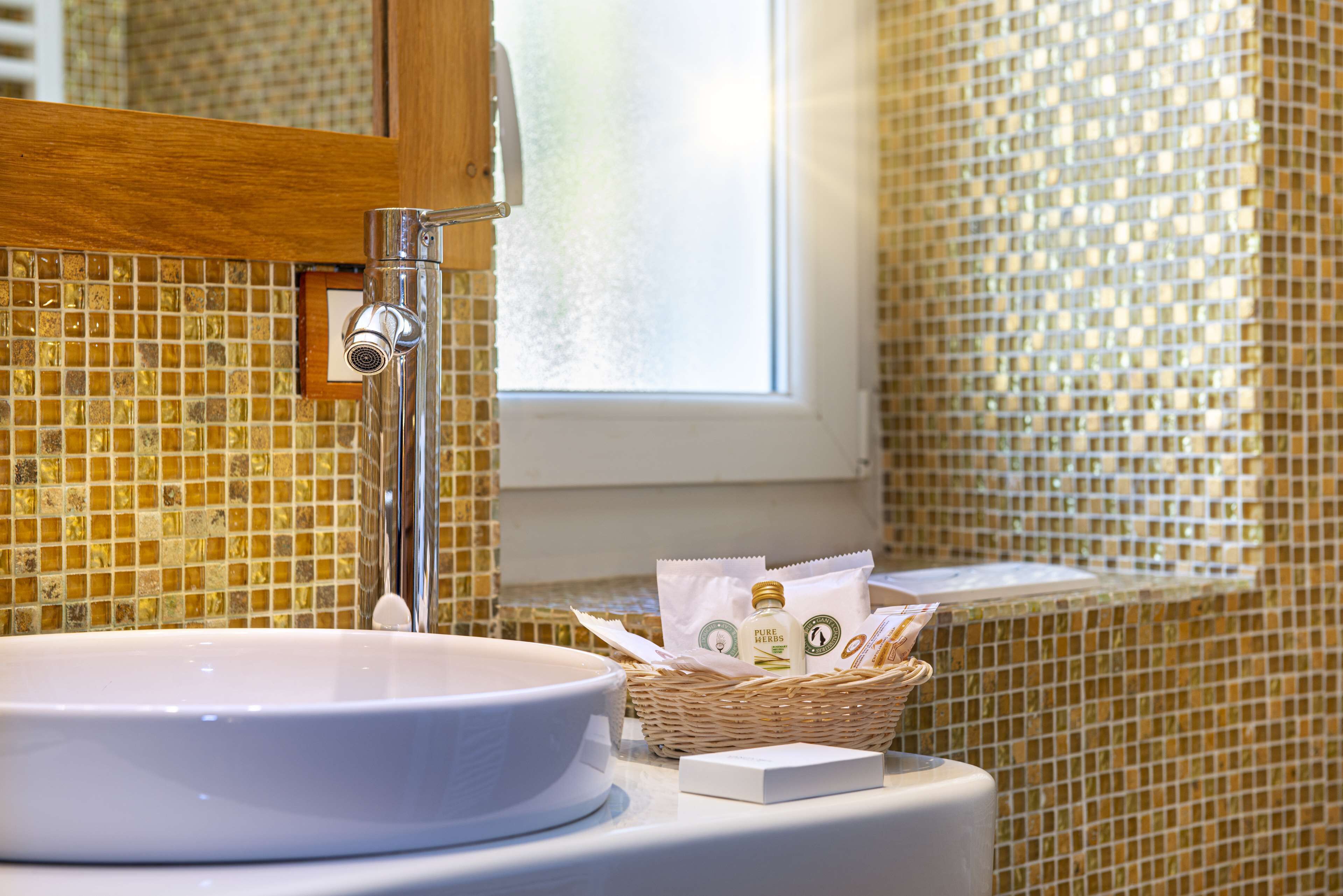Un baño con lavamanos blanco, un espejo y una ventana.