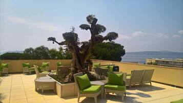 Una terrazza sul tetto con mobili in vimini e un grande albero.