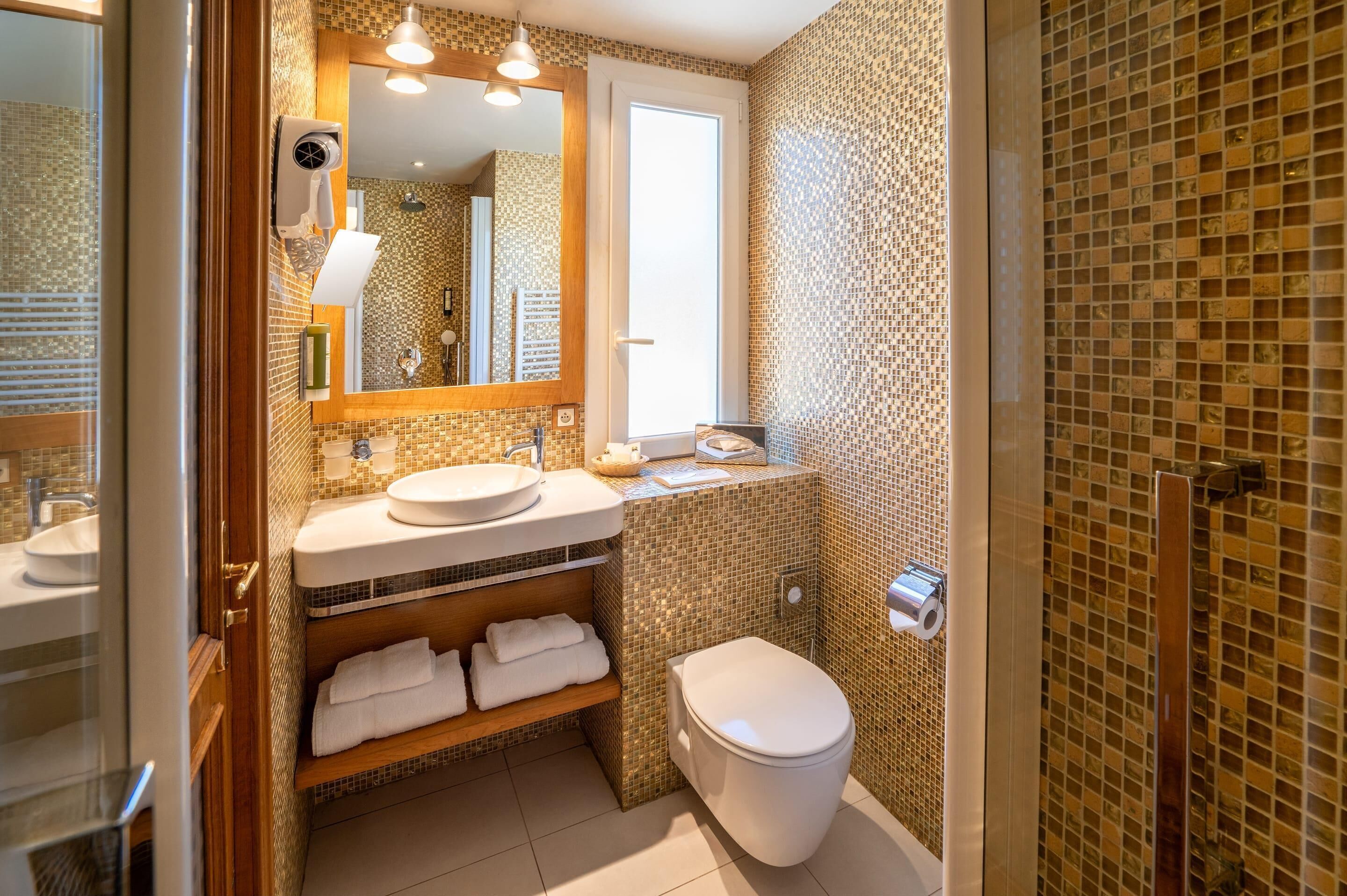 Un baño con lavamanos, espejo, toallero y retrete.