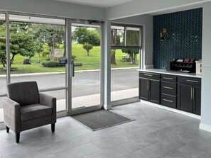 Un interior moderno con un divisor de vidrio corredero que da a un jardín, un sillón gris y una cocina negra con salpicadero de espiga.